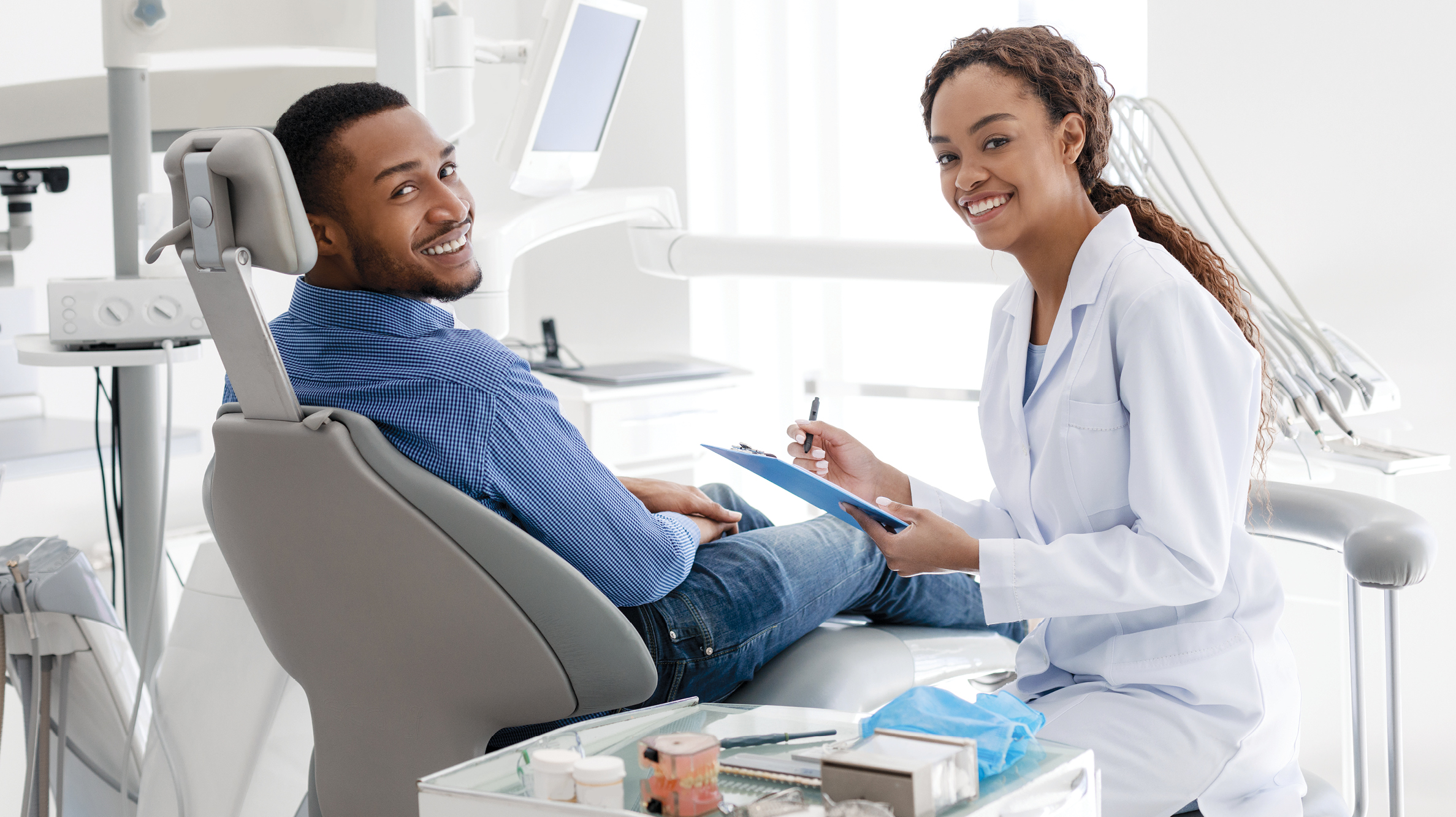 A dentist and a patient smiling during a dental treatment